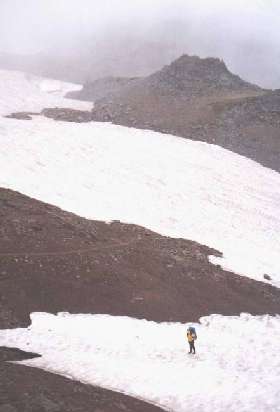 Crossing permanent snowfields along Panhandle Gap, slick from slushy rain. Along the Wonderland Trail in Mt. Rainier National Park